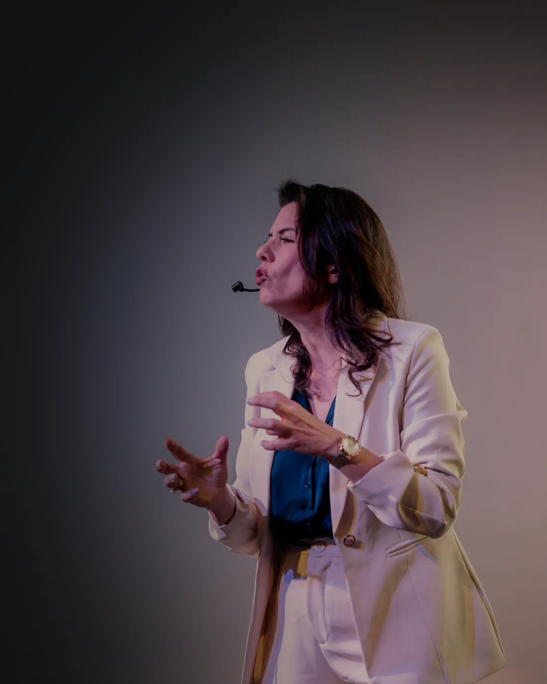 Renata Bertagnoli palestrando no palco, com microfone, falando para o público