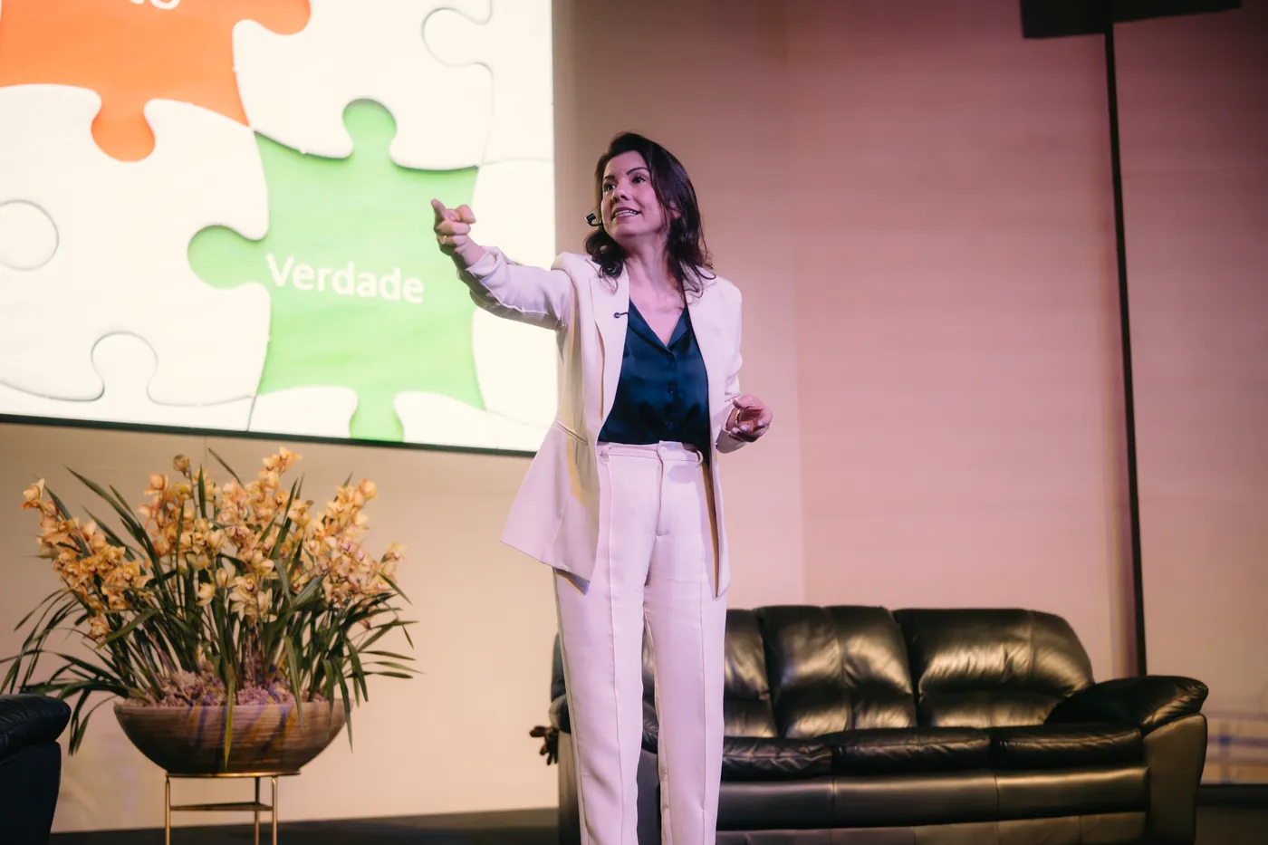 Renata Bertagnoli no palco, diante do telão, falando para o público